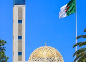 Capture of the Great Mosque of Algiers against a vibrant blue sky, featuring its dome and minaret.