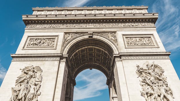 Stunning low angle shot of the Arc de Triomphe under a clear blue sky, capturing intricate details.