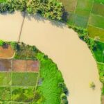Aerial image showcasing lush green farmland and a winding river, highlighting rural agriculture.
