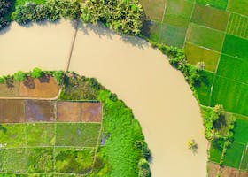 Aerial image showcasing lush green farmland and a winding river, highlighting rural agriculture.